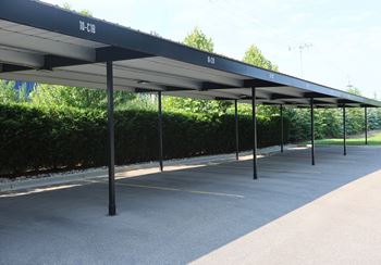 A long row of black canopies are over a parking lot